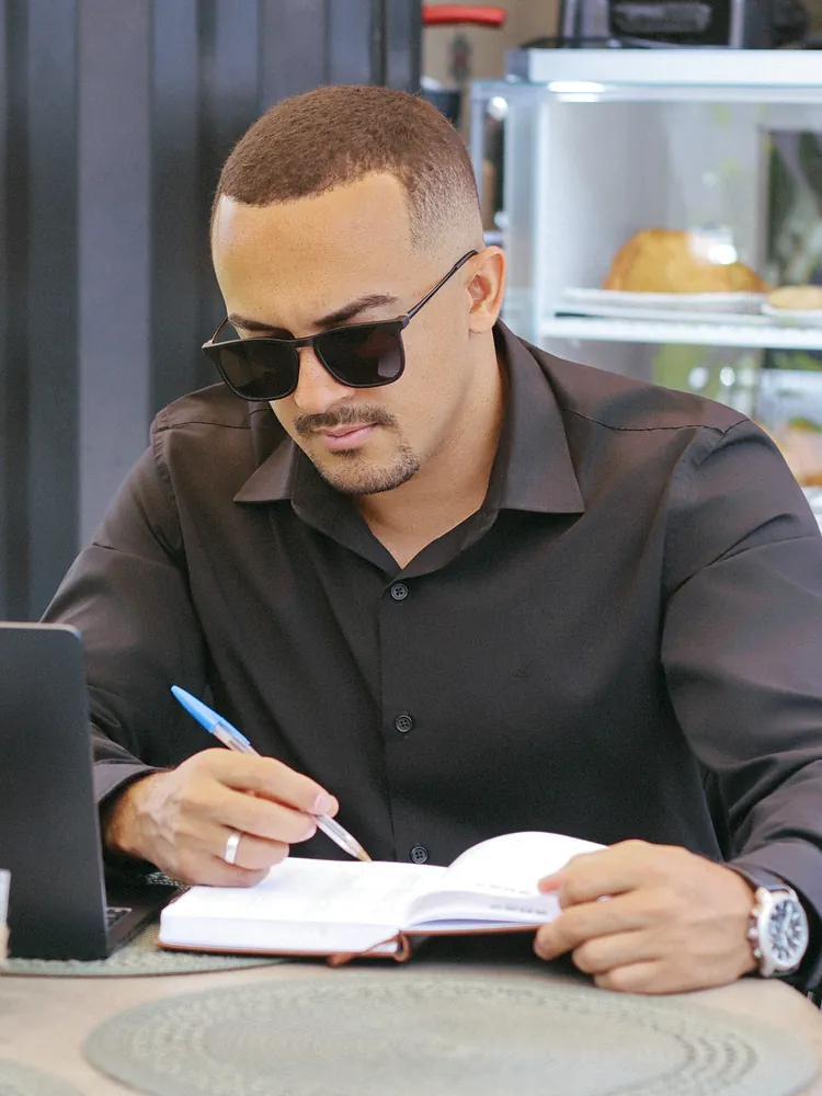Victor Oliveira fazendo anotações num caderno ao lado do notebook